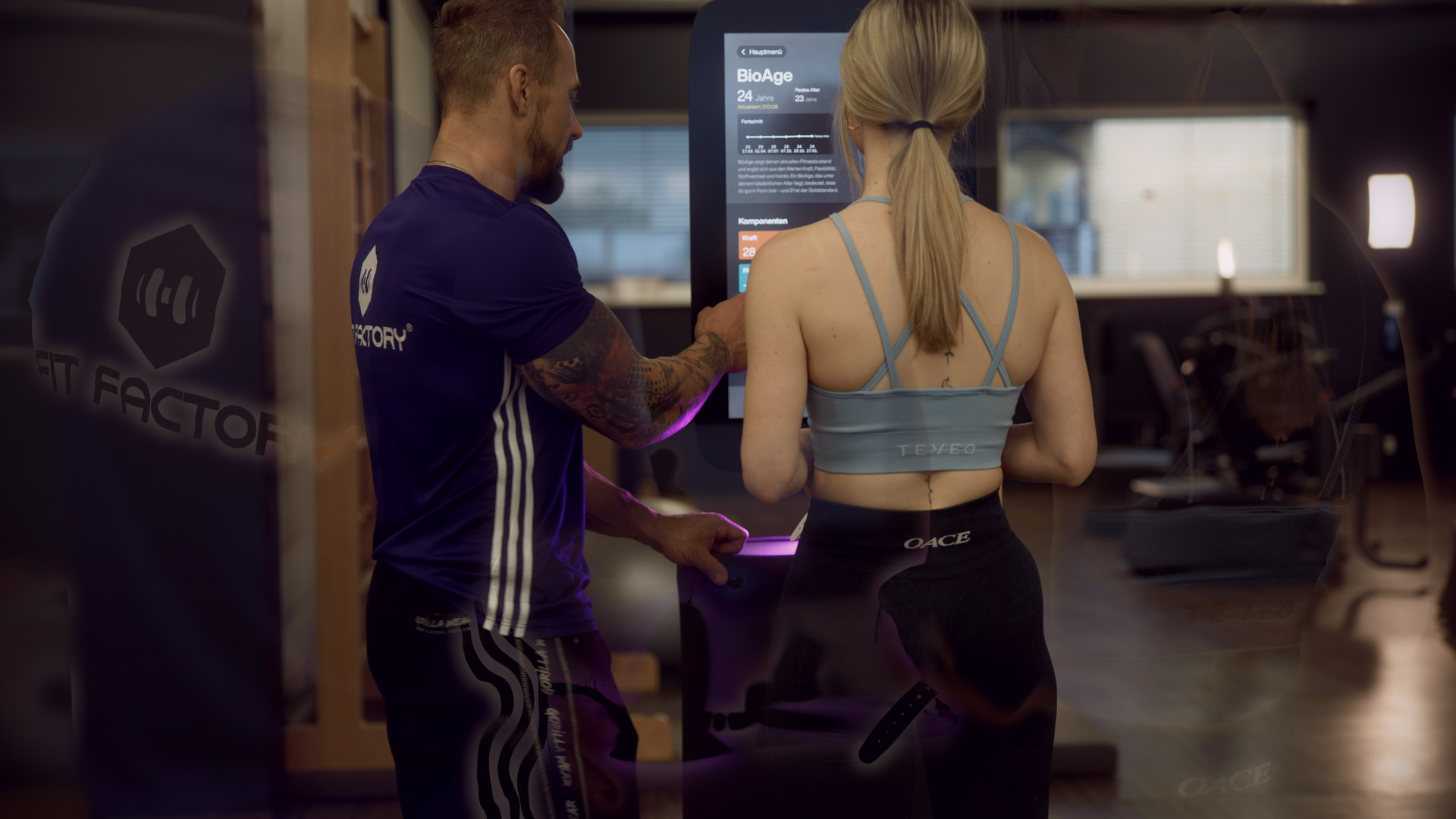 Ein FITfactory-Trainer begleitet ein Mitglied bei der Auswertung am Fitness Hub.