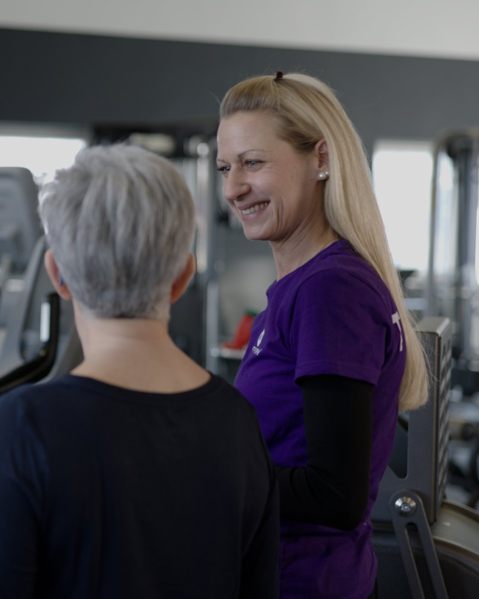 FITfactory-Teammitglied im Gespräch an einem Trainingsgerät